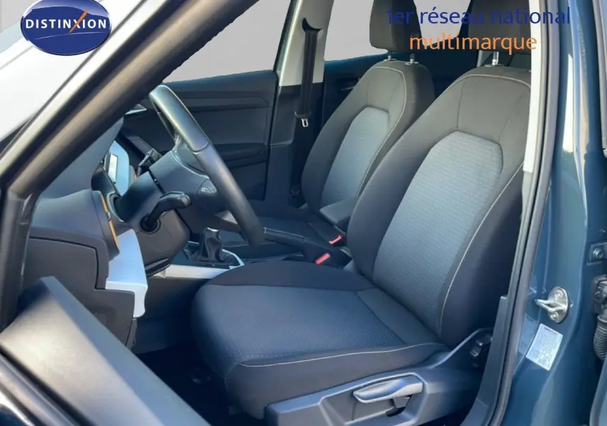 Vue intérieure côté conducteur du SEAT Arona gris Fiord, montrant les sièges tissu noir et la boîte manuelle.