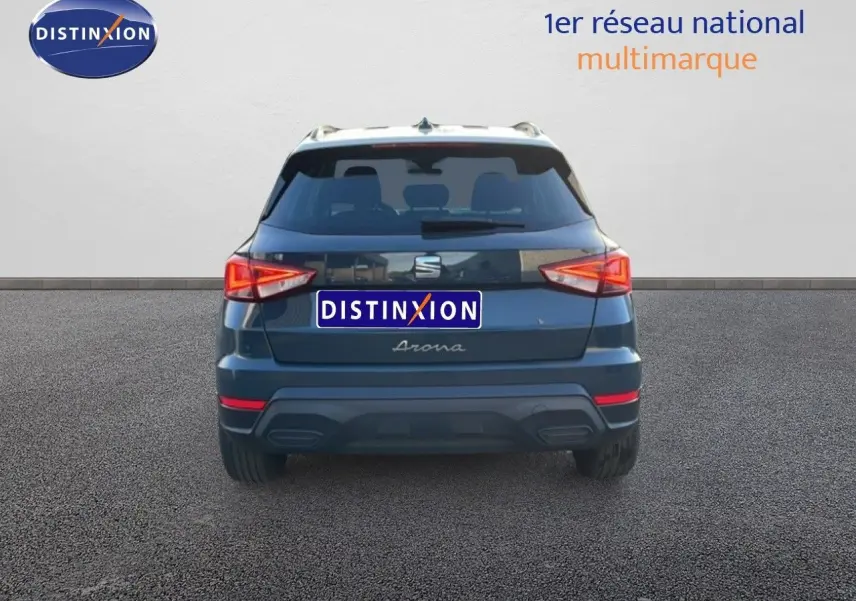 Vue arrière d’un SEAT Arona gris Fiord avec toit blanc, feux arrière allumés sur fond neutre.