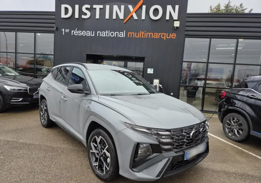 Hyundai Tucson 2025 gris métallisé en 3/4 avant droit, avec calandre N Line noire et jantes alliage 19 pouces.
