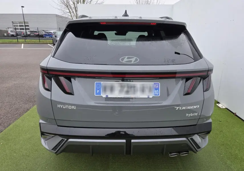 Vue arrière du Hyundai Tucson 2025 gris métallisé avec feux LED et double sortie d'échappement côté droit.