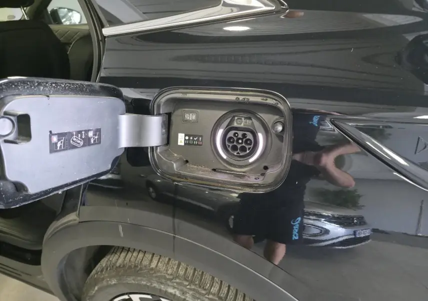 Détail de la trappe de recharge ouverte côté arrière droit sur DS7 Crossback E-Tense noir brillant.