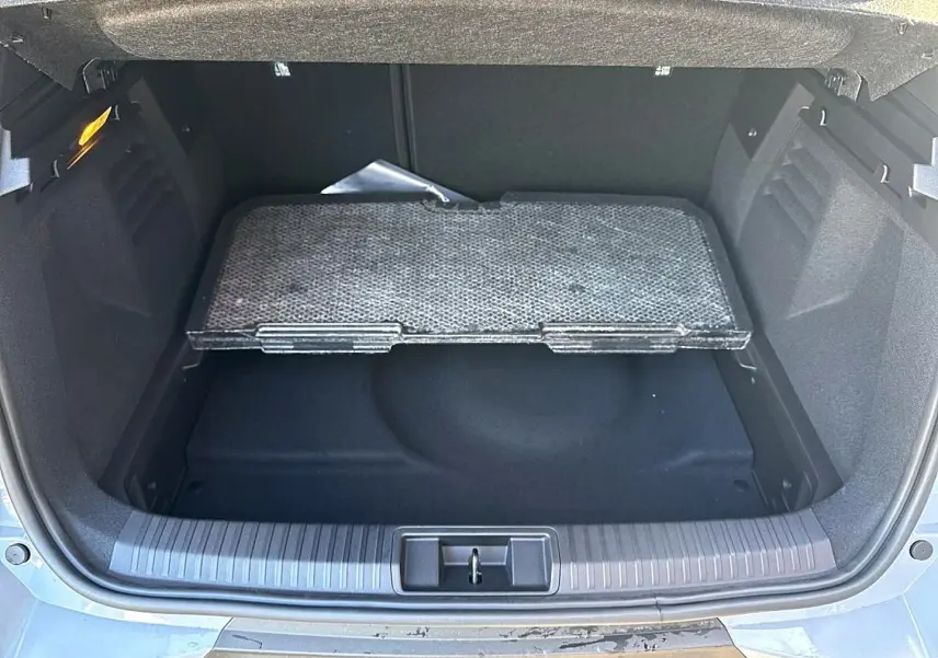 Coffre ouvert vu de l'arrière d'une Renault Symbioz gris rafale avec plancher de coffre mobile partiellement relevé.