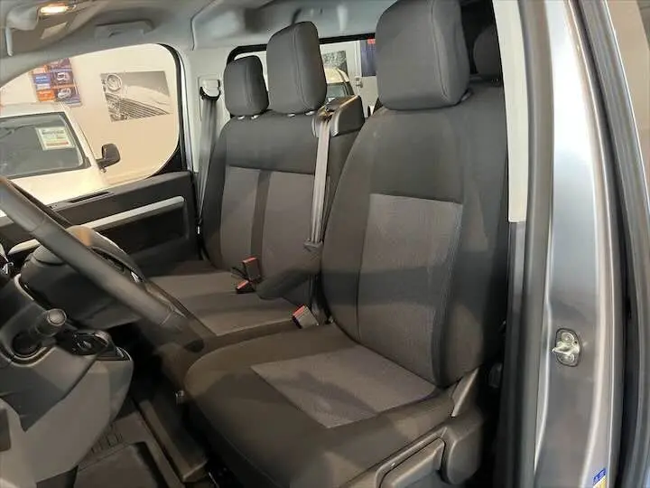 Vue intérieure côté conducteur du Fiat Scudo Cabine Approfondie gris Artense, montrant les sièges avant en tissu noir et gris.