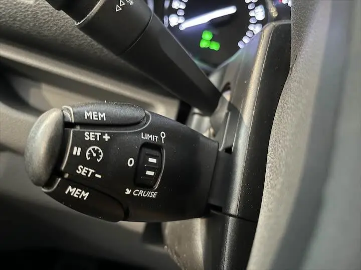 Gros plan sur la commande de régulateur de vitesse du FIAT Scudo gris Artense, avec tableau de bord flou en arrière-plan.