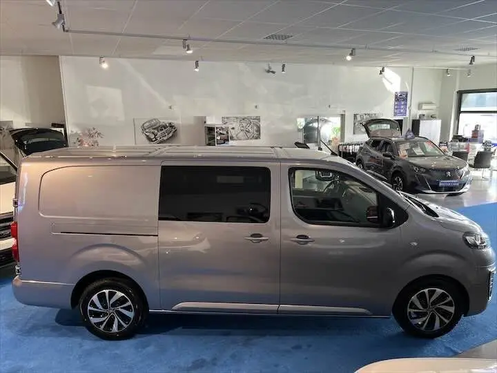 Profil côté droit du FIAT Scudo cabine approfondie gris Artense métal dans un showroom lumineux.
