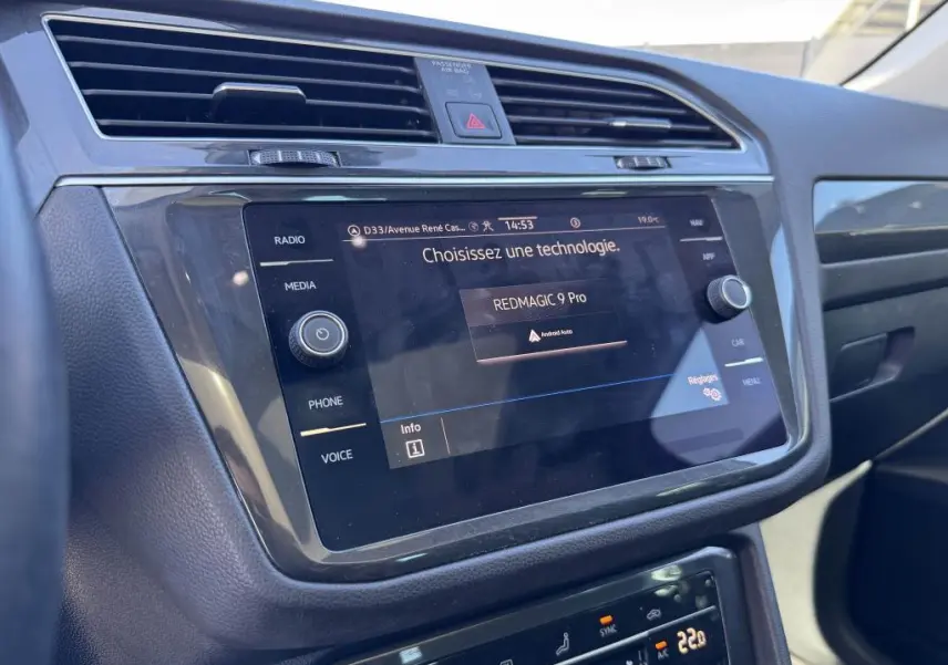 Vue rapprochée de l'écran tactile central du Volkswagen Tiguan gris 2021 avec commandes multimédia et climatisation digitale.
