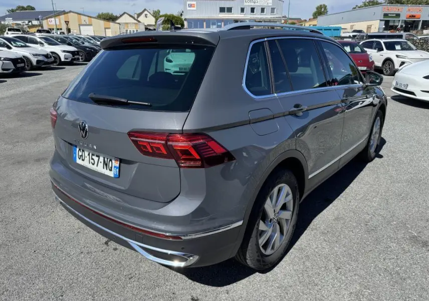 Vue 3/4 arrière droite d'un Volkswagen Tiguan gris avec feux arrière LED et jantes alliage 18 pouces sur parking.