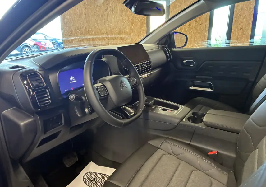Vue intérieure côté conducteur du Citroën C5 Aircross 2025, avec tableau de bord noir et écran digital allumé.