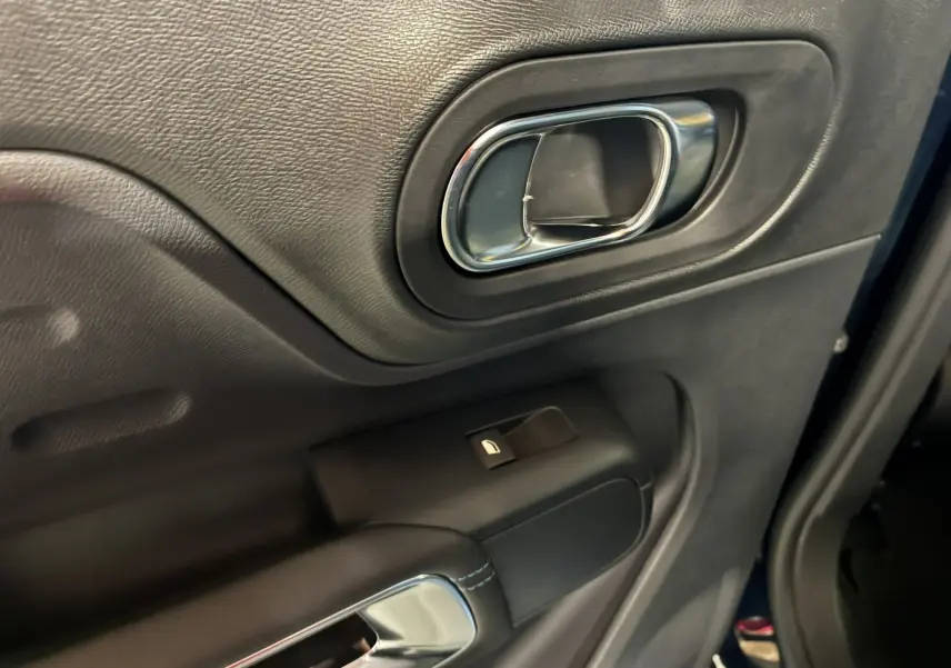 Gros plan sur la poignée intérieure chromée et le bouton de lève-vitre du côté gauche d'une Citroën C5 Aircross bleu Eclipse métal.