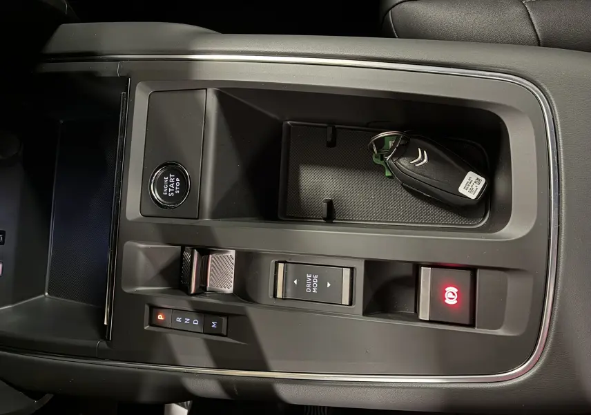 Vue rapprochée de la console centrale noire du Citroën C5 Aircross 2025 avec clé, bouton start et commandes de boîte auto.