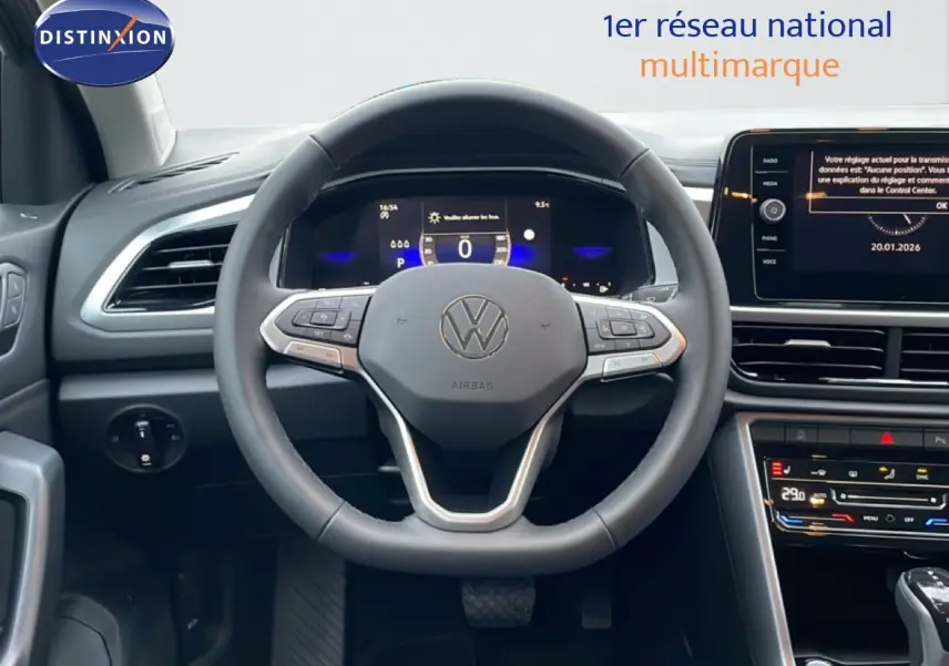 Vue intérieure centrée sur le volant noir du Volkswagen T-Roc avec tableau de bord digital et écran tactile.