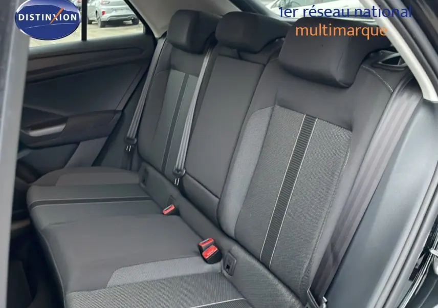 Vue intérieure côté arrière droit du Volkswagen T-Roc noir Grenadilla, montrant les sièges arrière en tissu et cuir avec ceintures de sécurité.