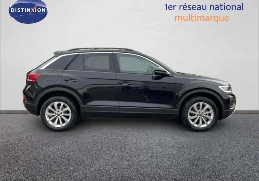 Profil latéral droit d’un Volkswagen T-Roc noir Grenadilla métallisé, avec jantes alliage et toit ouvrant visible.