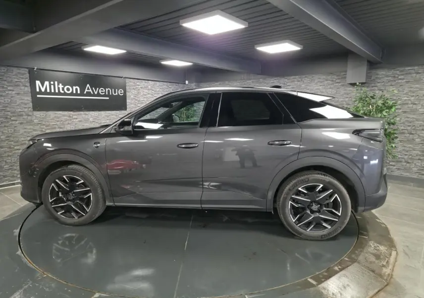 Profil côté gauche du Peugeot 3008 gris métallisé 2025 avec jantes alliage noires et toit noir en showroom.