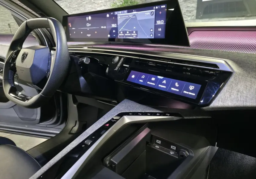 Vue intérieure côté conducteur du Peugeot 3008 gris 2025, avec tableau de bord numérique panoramique et console centrale moderne.
