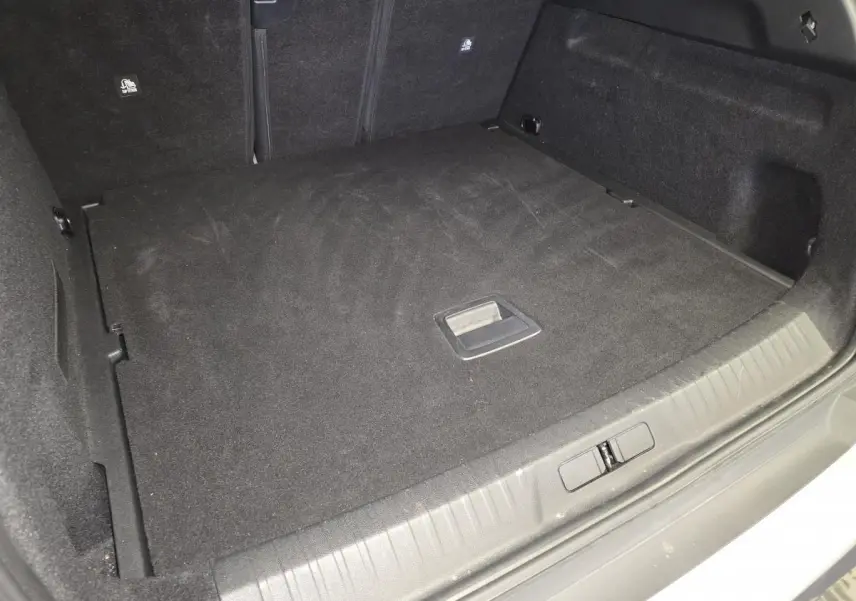 Coffre spacieux et propre du Peugeot 3008 gris, vue depuis l'arrière avec plancher plat et poignée centrale.
