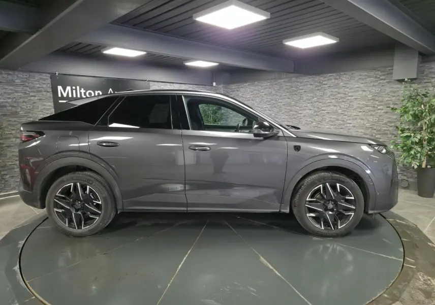 Peugeot 3008 gris en profil droit, jantes alliage noires, toit et vitres arrière teintés, intérieur visible.