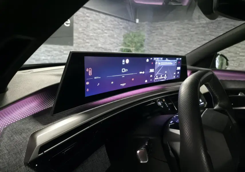 Vue intérieure du tableau de bord du Peugeot 3008 gris 2025 avec écran panoramique et éclairage d'ambiance violet.