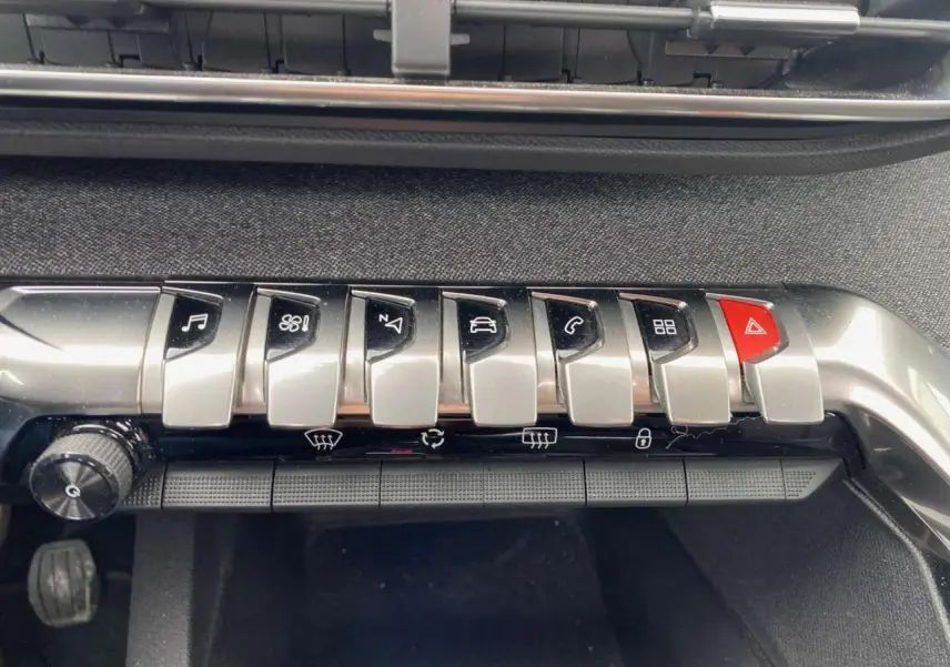 Gros plan sur la rangée de boutons argentés et rouge du tableau de bord du Peugeot 3008 blanc, version Allure+ 2019.