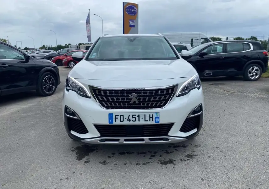 Vue avant d'un Peugeot 3008 blanc nacré avec calandre noire et barres de toit en aluminium sous un ciel nuageux.