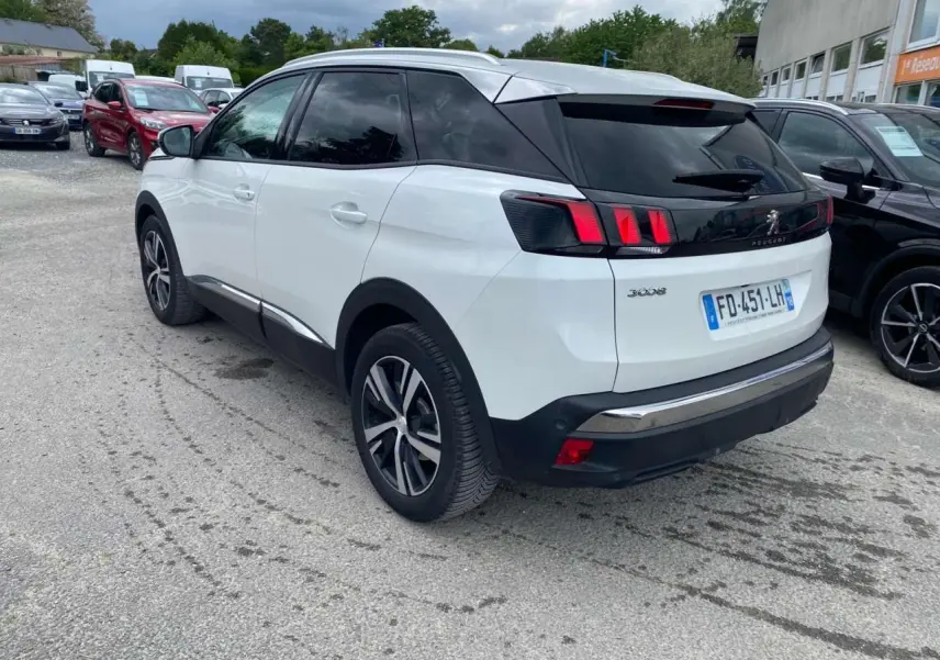 Vue 3/4 arrière gauche d'un Peugeot 3008 blanc nacré avec toit noir, jantes alliage et vitres surteintées.