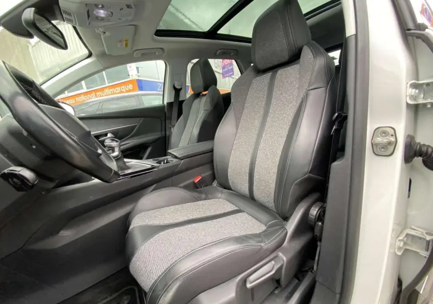 Vue intérieure côté conducteur du Peugeot 3008 blanc 2019, mettant en valeur la sellerie TEP et tissu et le toit ouvrant panoramique.