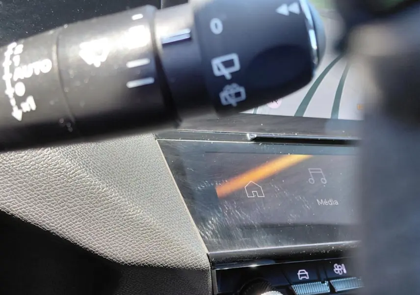 Détail du commodo de commandes et partie de l’écran tactile du tableau de bord dans l’habitacle d’une Peugeot 308 Hybrid gris.