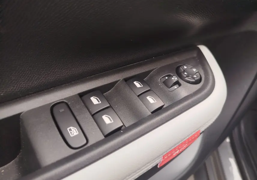 Gros plan sur les commandes de lève-vitres et réglage des rétroviseurs côté conducteur d'une Citroën C3 2025 gris foncé toit noir.