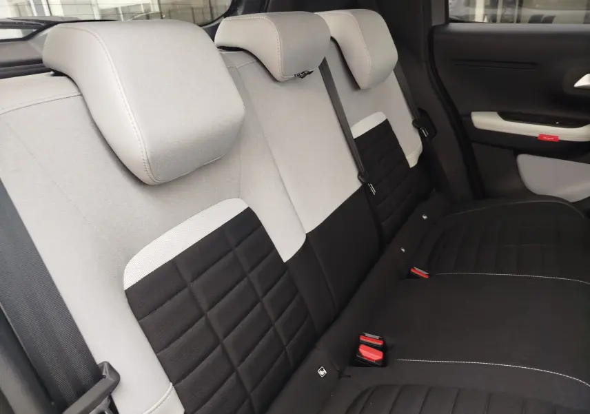 Vue intérieure des sièges arrière bi-ton gris clair et noir de la Citroën C3 2025, avec appuie-têtes et ceintures visibles.