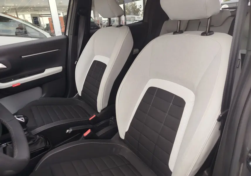 Vue intérieure des sièges avant bicolores gris clair et noir de la Citroën C3 2025 avec boîte manuelle.