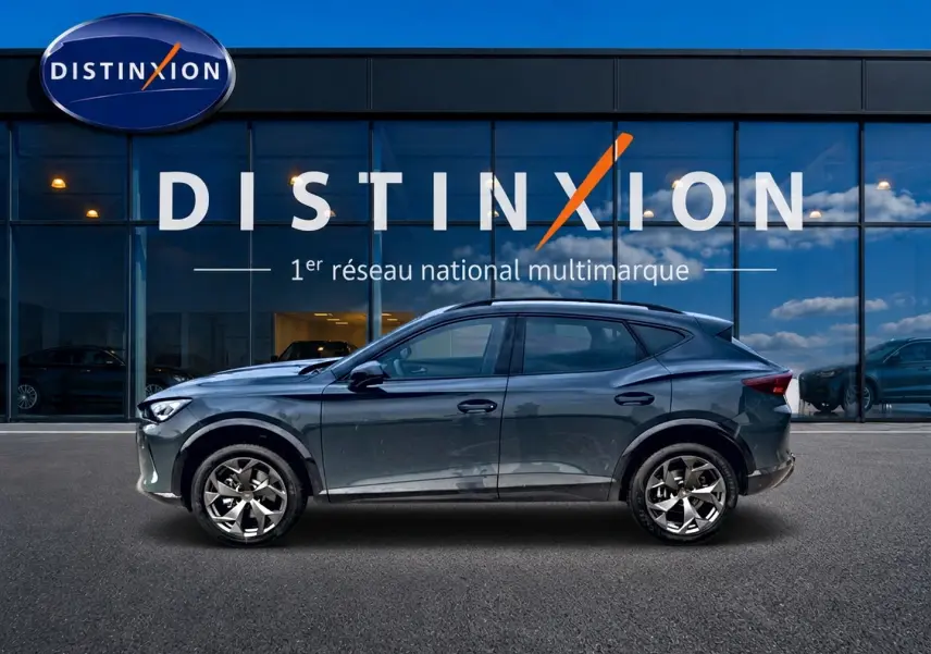 Vue de profil côté gauche du CUPRA Formentor 1.5 etsi hybrid bleu fjord avec jantes 18 pouces devant une vitrine Distinxion.