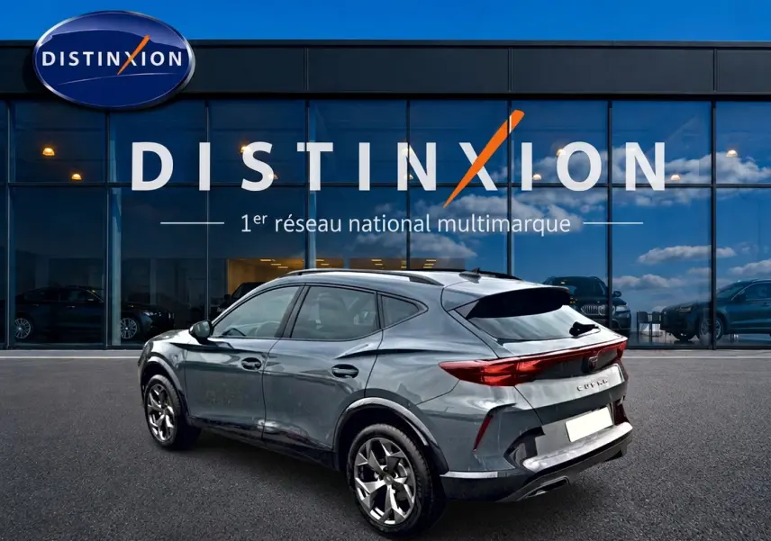 Vue 3/4 arrière droite d’un CUPRA Formentor bleu fjord 2026 avec feux arrière LED et jantes 18 pouces devant un showroom Distinxion.