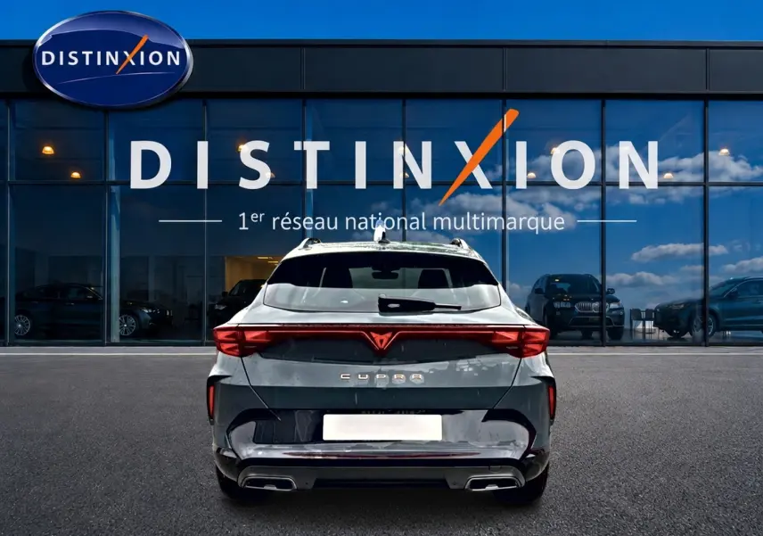 Vue arrière d'un CUPRA Formentor bleu fjord 2026 avec feux LED et double sortie d'échappement, devant un showroom Distinxion.