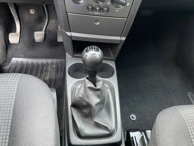 Le levier de vitesse manuel noir de l'Opel Meriva grise de 2010, vu de dessus entre les sièges avant.