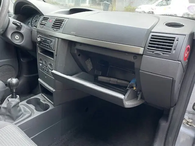 Intérieur avant droit de l’Opel Meriva grise de 2010, tableau de bord et boîte à gants ouverte visibles.