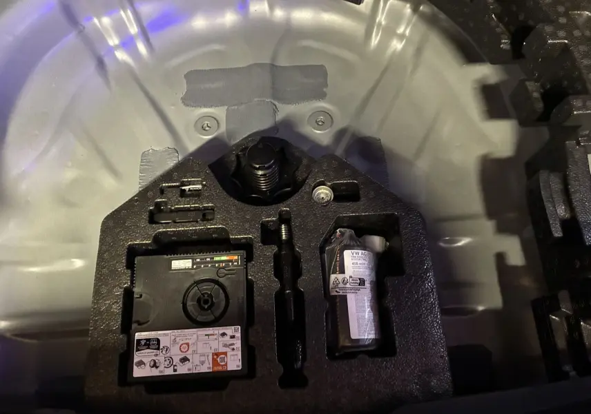 Gros plan sur le compartiment de rangement sous le coffre d’un CUPRA Formentor gris foncé 2024, montrant kit de réparation pneus.