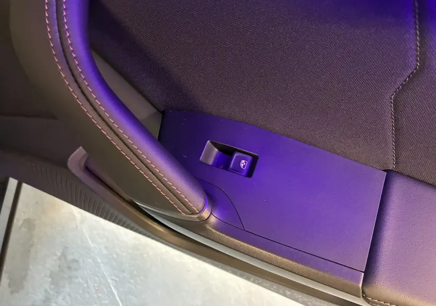 Gros plan sur le bouton de lève-vitre côté gauche avec surpiqûres rouges sur le panneau noir du CUPRA Formentor gris foncé 2024.