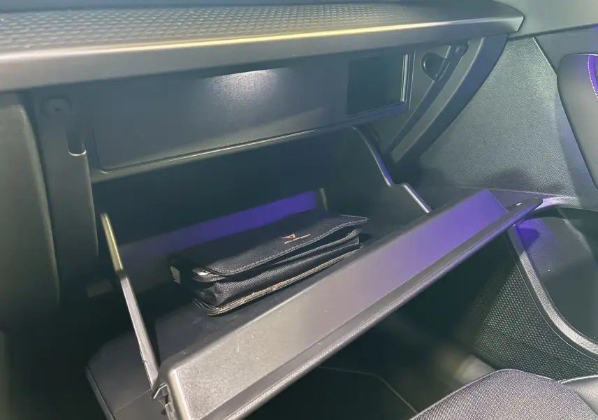 Gros plan sur la boîte à gants ouverte du CUPRA Formentor 2024, intérieur noir avec pochette siglée à l'intérieur.