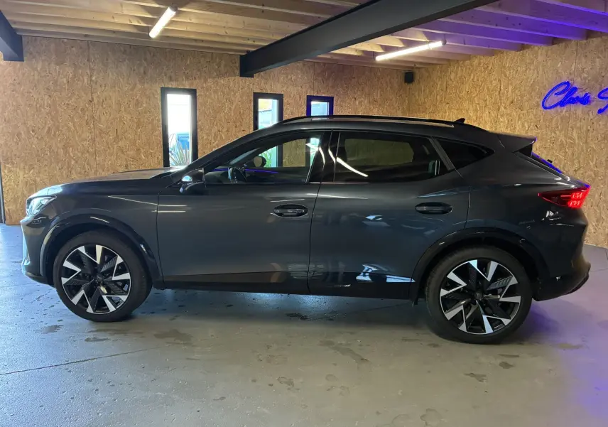 Vue latérale droite d'un CUPRA Formentor gris foncé 2024 avec jantes bi-ton et toit ouvrant en intérieur bois.