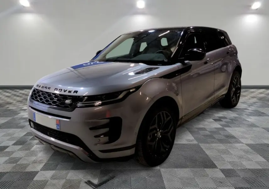 Vue 3/4 avant d'un Range Rover Evoque 200D SE R-Dynamic gris Eiger avec jantes noires, devant un showroom multimarque.