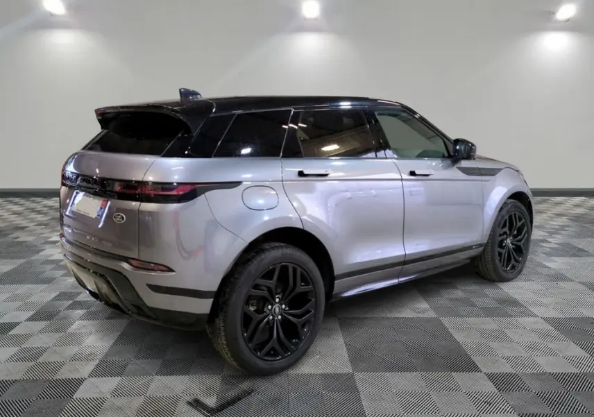 Range Rover Evoque 200D SE R-Dynamic gris Eiger en 3/4 arrière, roues noires et toit noir, stationné devant un showroom.