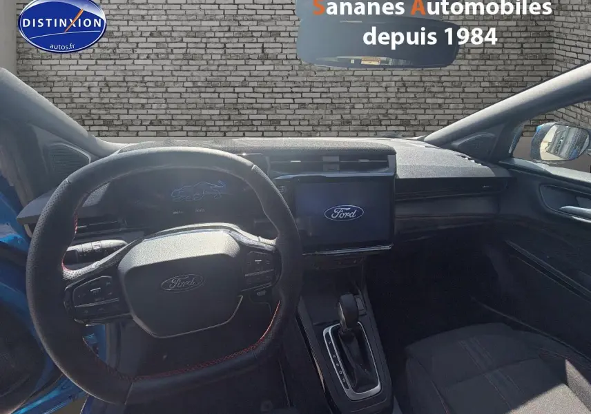 Vue intérieure du poste de conduite du Ford Puma bleu 2025, avec volant sport et écran tactile central allumé.