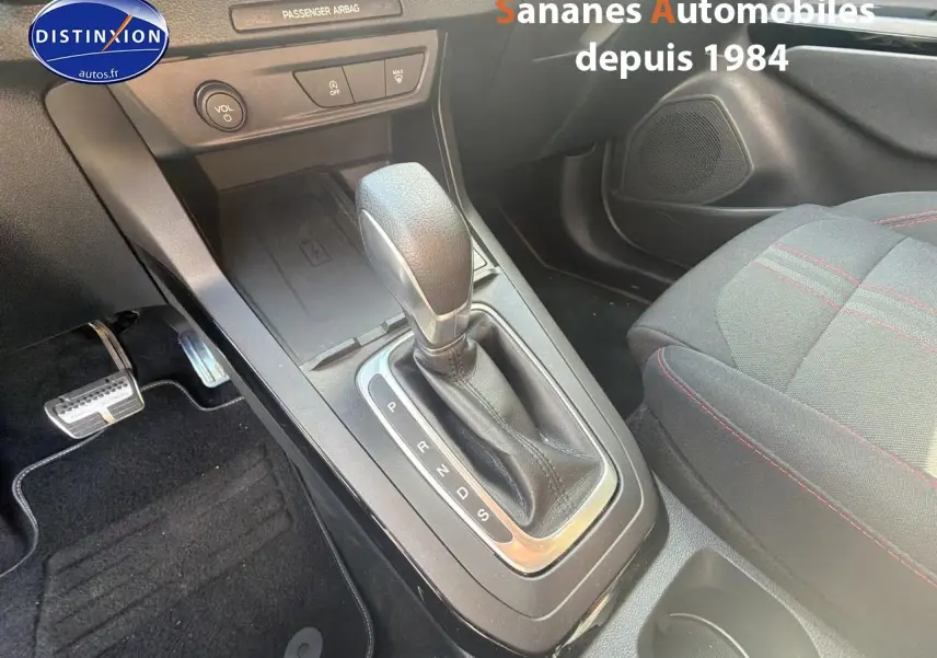 Gros plan sur la console centrale et levier de vitesse automatique du Ford Puma bleu avec surpiqûres rouges sur siège tissu.