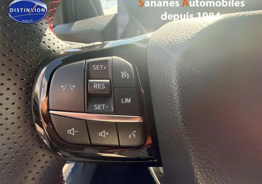Gros plan sur les commandes de régulateur de vitesse et volume au volant perforé du Ford Puma bleu 2025 finition ST-Line.