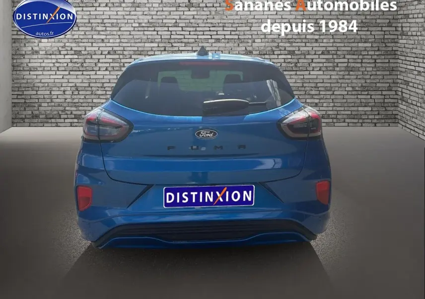 Vue arrière d'une Ford Puma bleu métallisé, avec hayon et feux arrière distinctifs dans un showroom.