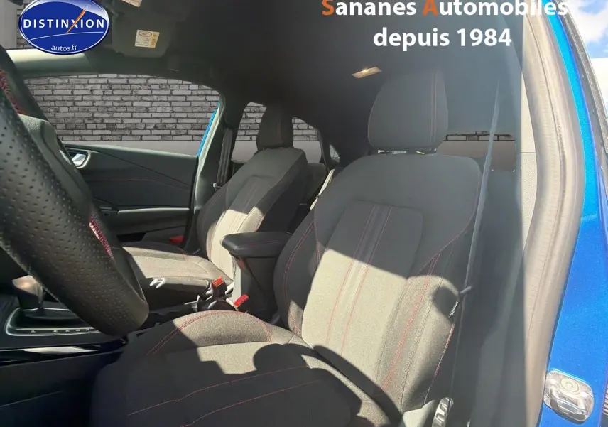 Vue intérieure côté gauche du Ford Puma bleu 2025, sièges tissu avec surpiqûres rouges et volant perforé.