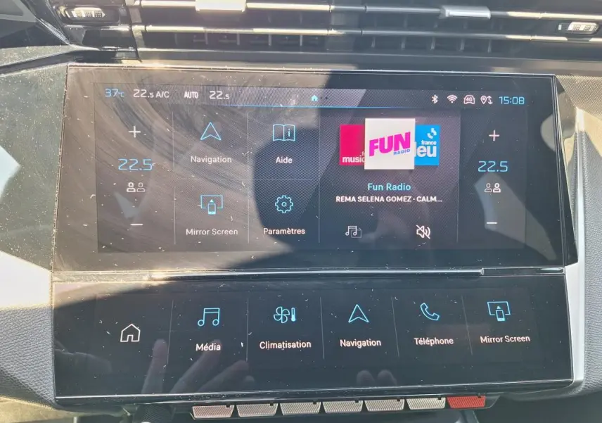 Vue rapprochée de l'écran tactile central du Peugeot 308 Hybrid 145 e-DCS6 GT 2025 avec interface multimédia et climatisation digitale.