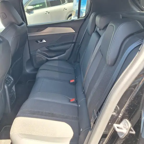Vue intérieure côté droit sur les sièges arrière noirs de la Peugeot 308 Hybrid 145 e-DCS6 GT 2025 avec finitions tissu et cuir.