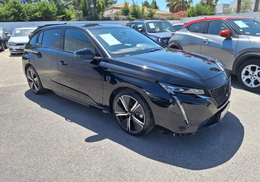 Peugeot 308 Hybrid 145 e-DCS6 GT noire vue en 3/4 avant droit, avec jantes alliage 18 pouces et vitres teintées.