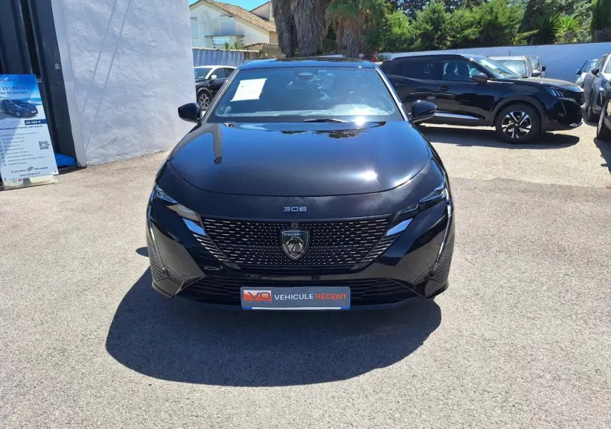 Vue frontale d'une Peugeot 308 Hybrid 145 e-DCS6 GT noire, avec calandre au lion et plaque "Véhicule récent".